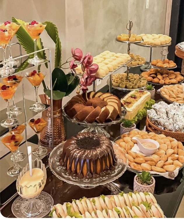 Mesa de coffee break com bolos, pães, croissants, sanduíches e frutas